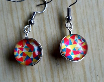 Puede incluir: Un par de pendientes de plata con patrones geométricos coloridos dentro de los cabujones redondos de vidrio.
