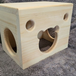 May include: A wooden toy with a bear-shaped cutout and a round hole. The toy is made of natural wood and has a light brown color.