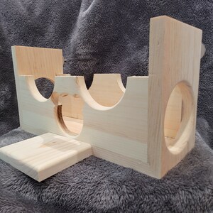 Puede incluir: Estructura de juego de madera para animales peque&ntilde;os, con varios t&uacute;neles y una plataforma. La estructura est&aacute; hecha de madera natural y tiene un color marr&oacute;n claro.