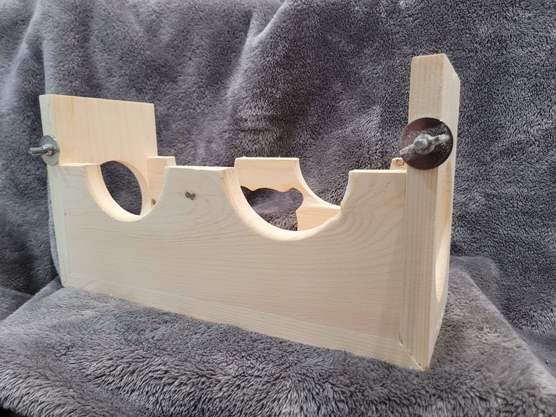 Puede incluir: Una jaula de h&aacute;mster de madera con tres niveles y un recorte en forma de coraz&oacute;n. La jaula est&aacute; hecha de madera natural y tiene dos tornillos de metal en el lateral.