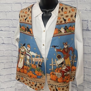 May include: A sleeveless vest featuring a blue background with a fall-themed print of scarecrows, pumpkins, and crows. The vest includes signs reading Pumpkin Farm and Pumpkin Patch, layered over a white button-down shirt with a collar and long sleeves.