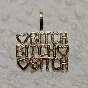 May include: Gold pendant necklace with the word "BITCH" repeated three times, with a heart symbol between each word.