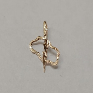 May include: A gold pendant charm in the shape of a lightning bolt inside a heart. The heart is outlined with a wavy line.