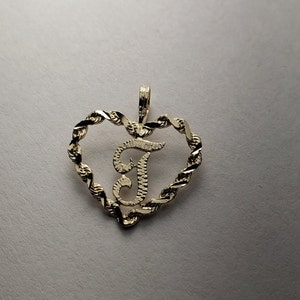 May include: Gold heart-shaped pendant with a cursive letter 'F' in the center. The heart is made of a twisted rope design.