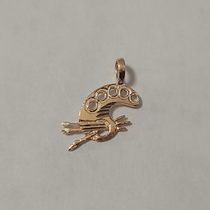 May include: Gold-toned pendant charm in the shape of a crescent moon with five circular cutouts. The moon has a textured surface and is attached to a small loop at the top. The pendant is approximately 2.5 cm in length.