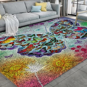 Puede incluir: Una colorida alfombra con diseño de mariposas. La alfombra tiene un fondo azul claro con un patrón de mariposas en varios colores, incluyendo rojo, naranja, amarillo, verde y morado. Los bordes de la alfombra son una mezcla de rosa, amarillo y verde.