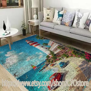 May include: A colorful area rug with a lighthouse, palm trees, and a beach scene. The rug has a blue background with white clouds and a sandy beach with cars and a sailboat.