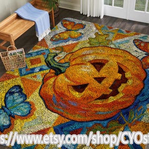 Op de afbeelding: Een kleurrijk vloerkleed met een grote, oranje pompoen met een uitgesneden gezicht. Vlinders en bladeren sieren het kleed, met blauwe, gele en oranje tinten. Ideaal voor Halloween-decoratie.