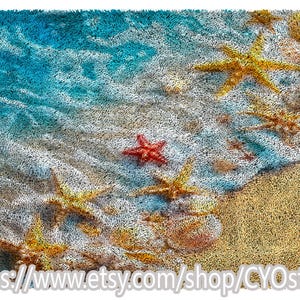 May include: A beach-themed rug with a textured design. The rug features a depiction of a sandy beach with blue water and several starfish in shades of red and yellow. The Etsy shop URL is visible at the bottom.
