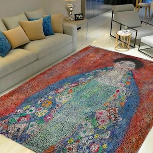 May include: A colorful rug with a painting of a woman in a blue dress with floral details on a red background.
