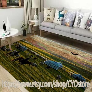 May include: A green, yellow, and brown area rug with a scene of a flock of sheep grazing in a field with a sunset in the background. The rug is laid out on a light gray sofa in a living room.
