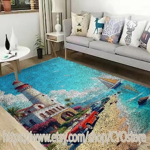 May include: A blue and beige area rug with a lighthouse, palm trees, and a red car on a beach scene. The rug is in a living room with a gray couch and pillows.