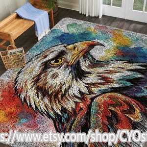 May include: A large area rug featuring a detailed, colorful illustration of an eagle's head. The eagle is depicted with white, brown, yellow, red, and blue hues. The rug has a soft, textured appearance and is suitable for a living room or bedroom.