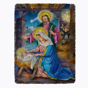 May include: A Christmas nativity scene with Mary, Joseph, and baby Jesus. Mary is wearing a blue robe with a gold trim and Joseph is wearing a green robe with a pink trim. The baby Jesus is lying in a manger with a white blanket. The scene is set in a barn with a wooden roof and a straw floor.