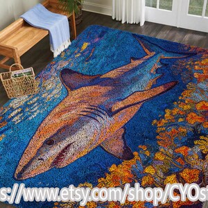 Peut inclure: Un tapis rectangulaire avec une illustration détaillée d'un requin nageant dans un océan bleu. Le requin est principalement orange et blanc, avec un design détaillé. Le tapis a un fond bleu avec du corail orange et jaune.