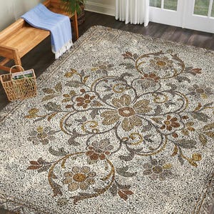 Peut inclure: Un grand tapis rectangulaire avec un motif floral dans des tons de marron, beige et vert. Le tapis a un aspect texturé et une bordure à franges. Un banc en bois avec une couverture bleue et un panier en osier sont en arrière-plan.