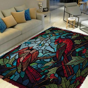 Puede incluir: Una alfombra de estilo vitral con dos cardenales rojos posados en ramas con hojas verdes y bayas rojas. La alfombra tiene un fondo azul oscuro con tonos de verde, azul y rojo.