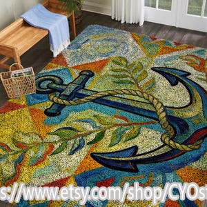 Op de afbeelding: Een kleurrijk vloerkleed met nautisch thema met een groot blauw anker met een touw, tegen een achtergrond van geometrische vormen in geel, oranje en blauw. Groene bladertakken voegen details toe. Het vloerkleed is een decoratieve vloerbedekking.