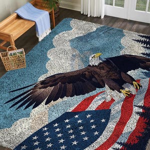 May include: A rectangular area rug featuring a bald eagle in flight with wings spread wide. The design includes a blue sky background with white clouds, a forest of dark pine trees, and a prominent American flag with red stripes and white stars.