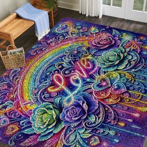 May include: A colourful, plush area rug with a rainbow, roses, hearts, and the word "Love" in a cursive font. The rug's colour palette includes shades of purple, blue, green, yellow, and pink, creating a whimsical design.