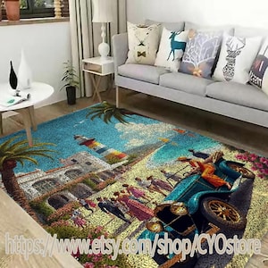 May include: A colorful area rug with a seaside scene featuring a lighthouse, palm trees, a vintage car, and people walking along a beach. The rug has a textured, pebble-like surface.