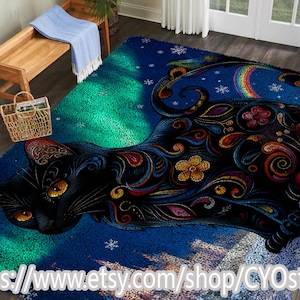 May include: A rectangular rug featuring a stylized black cat with intricate floral and swirl patterns in vibrant colors. The rug has a blue background with a green aurora borealis effect and a rainbow. The Etsy shop URL is visible at the bottom.