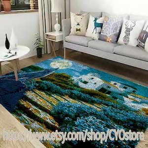 May include: A blue and green area rug with a wolf howling at the moon, a white house, and a field of flowers. The rug is in a living room with a gray couch and pillows.