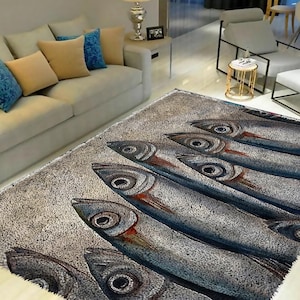 Op de afbeelding: Een grijs en wit vloerkleed met een herhalend patroon van gestileerde vissen met blauwe, rode en bruine details. De vissen zijn in rijen gerangschikt en kijken in dezelfde richting.