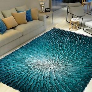 May include: A teal blue area rug with a white and teal circular pattern. The rug has a soft, plush texture.