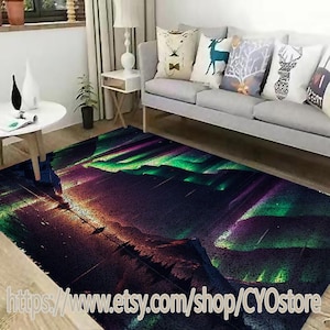 May include: A colorful rug with a mountain scene and a green and purple aurora borealis in the sky. The rug is on a wooden floor in a living room with a couch and pillows.