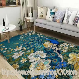 Könnte beinhalten: Ein türkisfarbener Pfauenteppich mit einem detaillierten Design mit einem Pfau, weißen und gelben Blumen und Pfauenfedern. Der Teppich befindet sich in einem Wohnzimmer mit einem grauen Sofa und dekorativen Kissen.