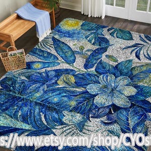 May include: A large area rug with a vibrant blue and white floral design. The rug features large, stylized leaves and flowers in shades of blue, with a white and gray background. The rug is placed on a hardwood floor.