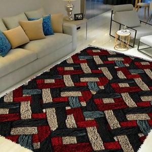 May include: A geometric patterned rug with black, red, beige, and blue colors. The rug has a shaggy texture and is made of a soft material.