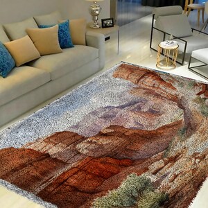 May include: A fluffy, white rug with a colorful, abstract design of a mountain range. The rug has a brown, orange, and green color scheme.