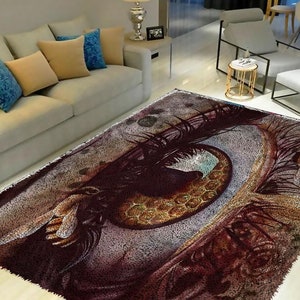 May include: A close-up of a colorful rug with a large eye design. The eye is surrounded by intricate details, including a honeycomb pattern and bees. The rug has a soft, plush texture.