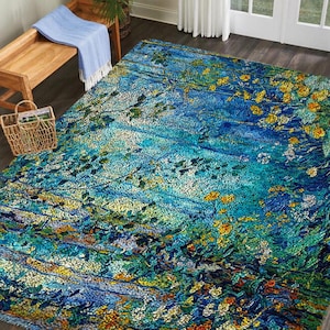 May include: A rectangular area rug with a vibrant, impressionistic design. The rug features a blend of blues, greens, and yellows, with a pattern resembling a floral landscape. The rug is placed on a wooden floor, with a bench and basket visible.