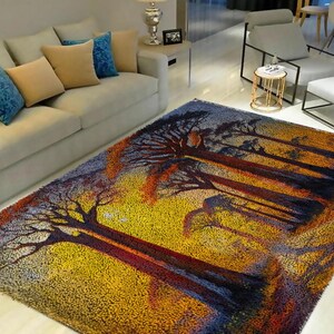Puede incluir: Una alfombra de área colorida con un diseño de árboles en un bosque. La alfombra tiene tonos de azul, amarillo, naranja y rojo.