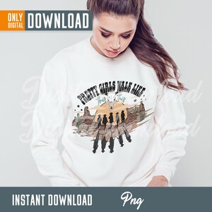 May include: A white sweatshirt with a graphic design of a sunset scene with cacti and a skull. The text "Pretty Girls Walk Like This" is written above the scene.