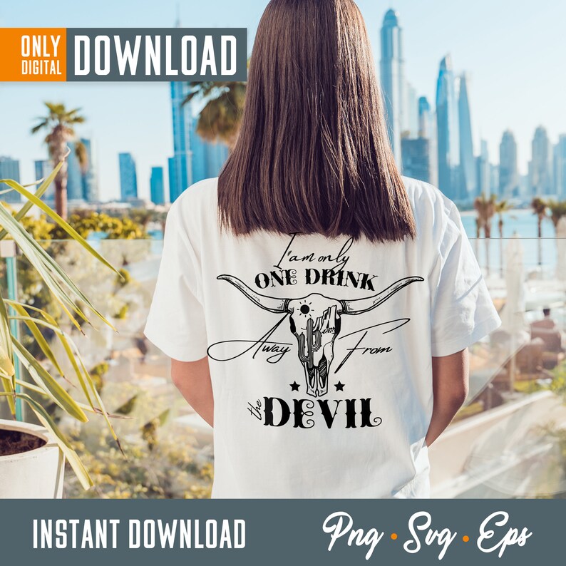 Op de afbeelding: Wit T-shirt met een zwarte afbeelding van een schedel met hoorns en de tekst "Ik ben maar &eacute;&eacute;n drankje verwijderd van de duivel".