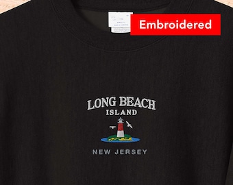 Può includere: Felpa nera con un ricamo che dice "Long Beach Island, New Jersey" e raffigura un faro con uccelli che volano sopra.