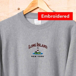 May include: Gray sweatshirt with embroidered text "Long Island New York" and a small graphic of a lighthouse on an island.