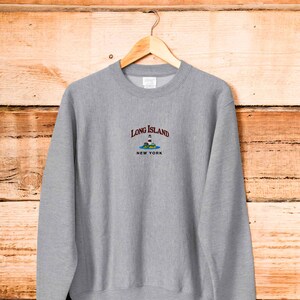 May include: Gray sweatshirt with a white embroidered lighthouse graphic and the text "Long Island New York".