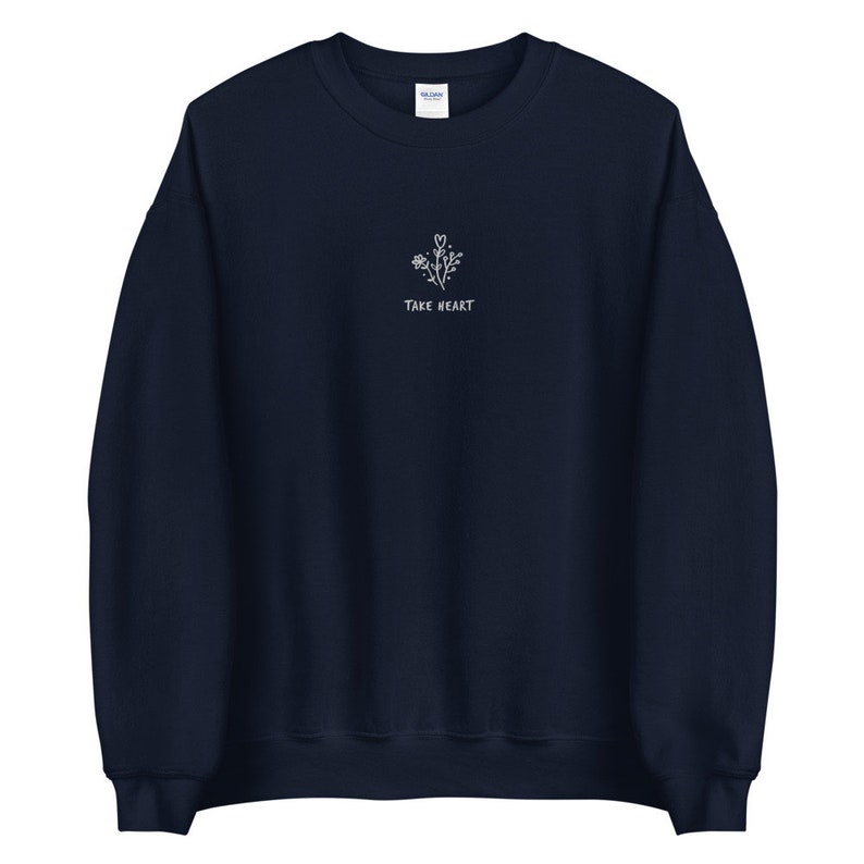 May include: Navy blue sweatshirt with a white embroidered design of flowers and the text "Take Heart".
