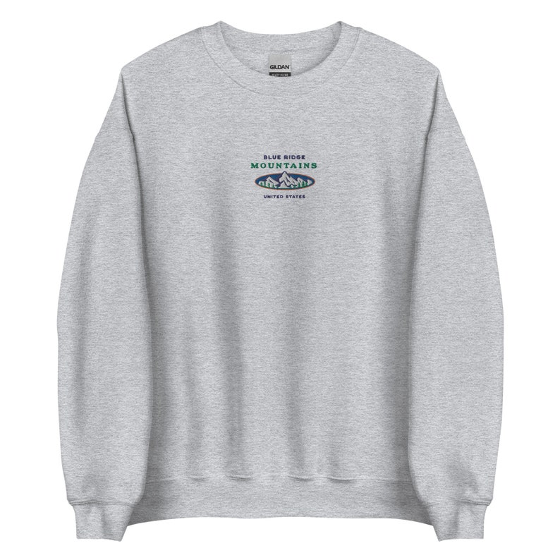 Op de afbeelding: Een grijs sweatshirt met een blauw en groen geborduurd logo met de tekst "Blue Ridge Mountains" en "United States".