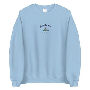 May include: Light blue sweatshirt with an embroidered design of a lighthouse on a small island with the text "Long Island, New York".