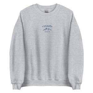 May include: A heather grey sweatshirt with a navy blue mountain graphic and the text "I lift my eyes to the mountains, Psalm 121".