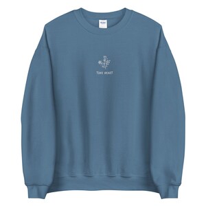 May include: A blue sweatshirt with a white embroidered design of flowers and the text "Take Heart".