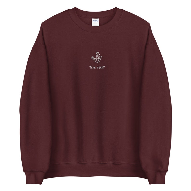 May include: Burgundy sweatshirt with a white embroidered design of a flower with the text "Take Heart".