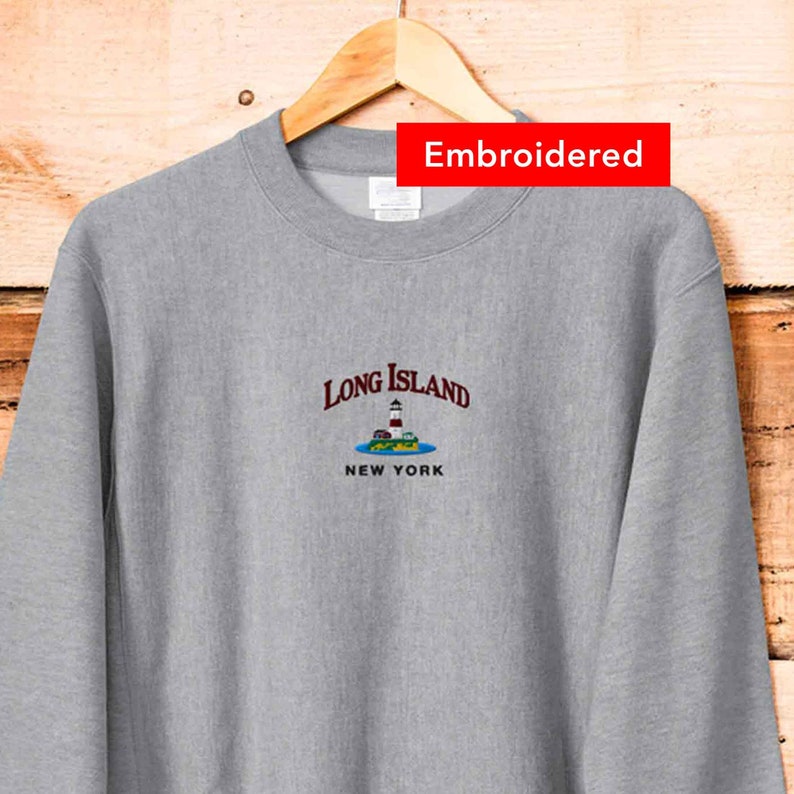 May include: Gray sweatshirt with embroidered text "Long Island New York" and a small graphic of a lighthouse on an island.