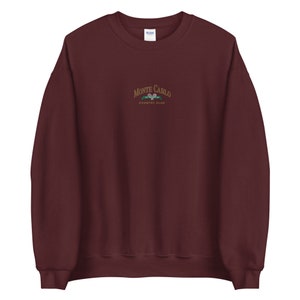 May include: A maroon sweatshirt with a gold embroidered logo that says "Monte Carlo Country Club" with a tennis racket graphic.